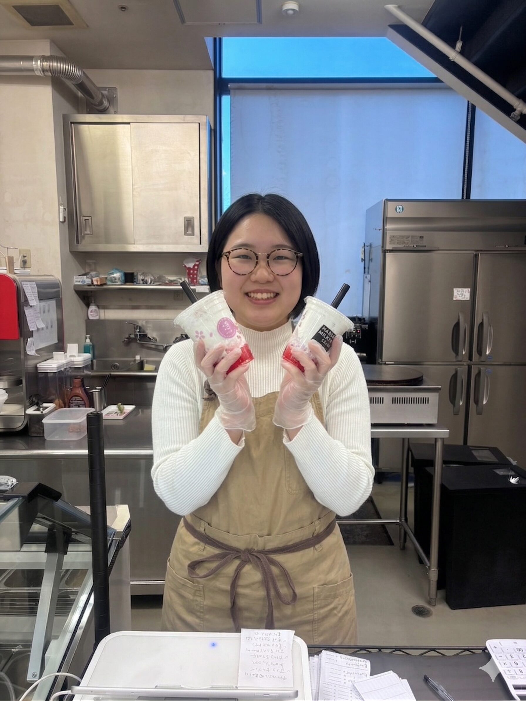 デザートドリンクを両手に持ち笑顔で立つスタッフ・商品提供のイメージ